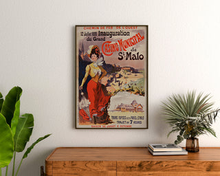 Vintage-Poster Bretagne – Saint-Malo, Eröffnung des Casinos, gerahmt über einer Holzkommode, zwischen Pflanzen.