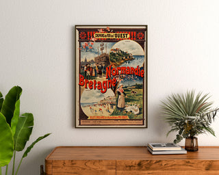 Vintage-Normandieplakat – Normandie und Bretagne — Chemins de fer de l’Ouest, gerahmt über einer Holzkommode, zwischen Pflanzen.