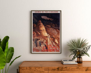 Vintage-Reiseplakat – Grottes de Lacave, Rocamadour, gerahmt über einer Holzkommode zwischen Pflanzen.
