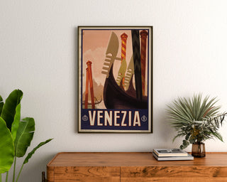 Vintage-Reiseplakat – Venezia, Gondolenspitzen, gerahmt über einer Holzkommode zwischen Pflanzen.