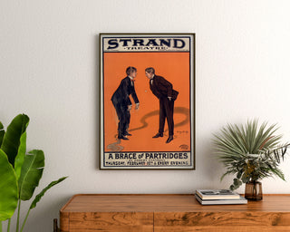 Vintage-Plakat A Brace of Partridges, Strand Theatre, gerahmt über einer Holzkommode, zwischen Pflanzen.