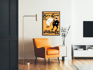 Vintage-Plakat Dudley Hardy, comic guide, gerahmt in einem Wohnzimmer mit orangefarbenem Sessel und Stehleuchte.