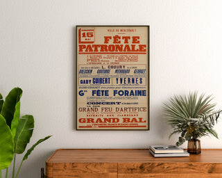Vintage-Poster Le Merlerault, Kirmes, gerahmt über einer Holzkommode zwischen Pflanzen.