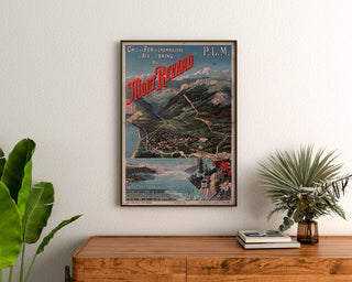 Vintage-Poster Mont-Revard, Zahnradbahn, gerahmt über einer Holzkommode zwischen Zimmerpflanzen.