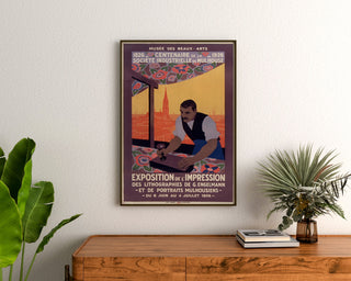 Vintage-Plakat Mulhouse, lithografische Ausstellung, gerahmt über einer Holzkommode zwischen Pflanzen.