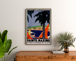 Vintage-Poster Sainte-Maxime, Côte des Maures, gerahmt über einer Holzkommode zwischen Pflanzen.