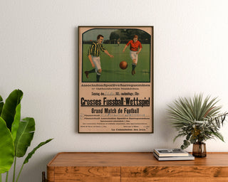 Vintage-Poster Sarreguemines, Fußballspiel, gerahmt über einer Holzkommode zwischen Pflanzen.
